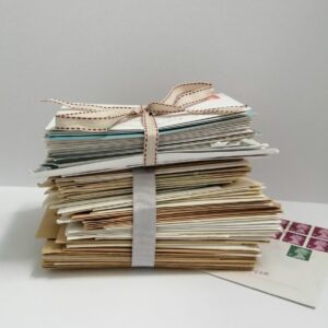 Bundles of envelopes tied with ribbon on and envelope with several stamps.